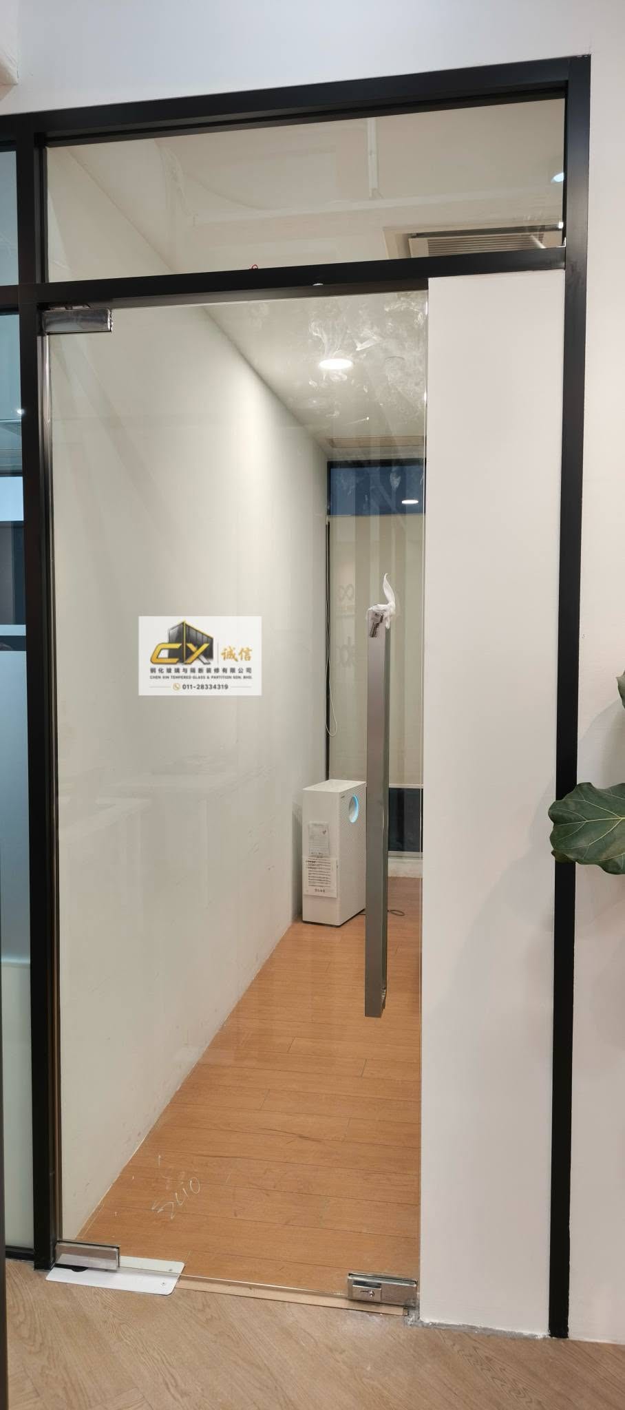 黑框玻璃门和侧板，门外是木纹地板的走廊。