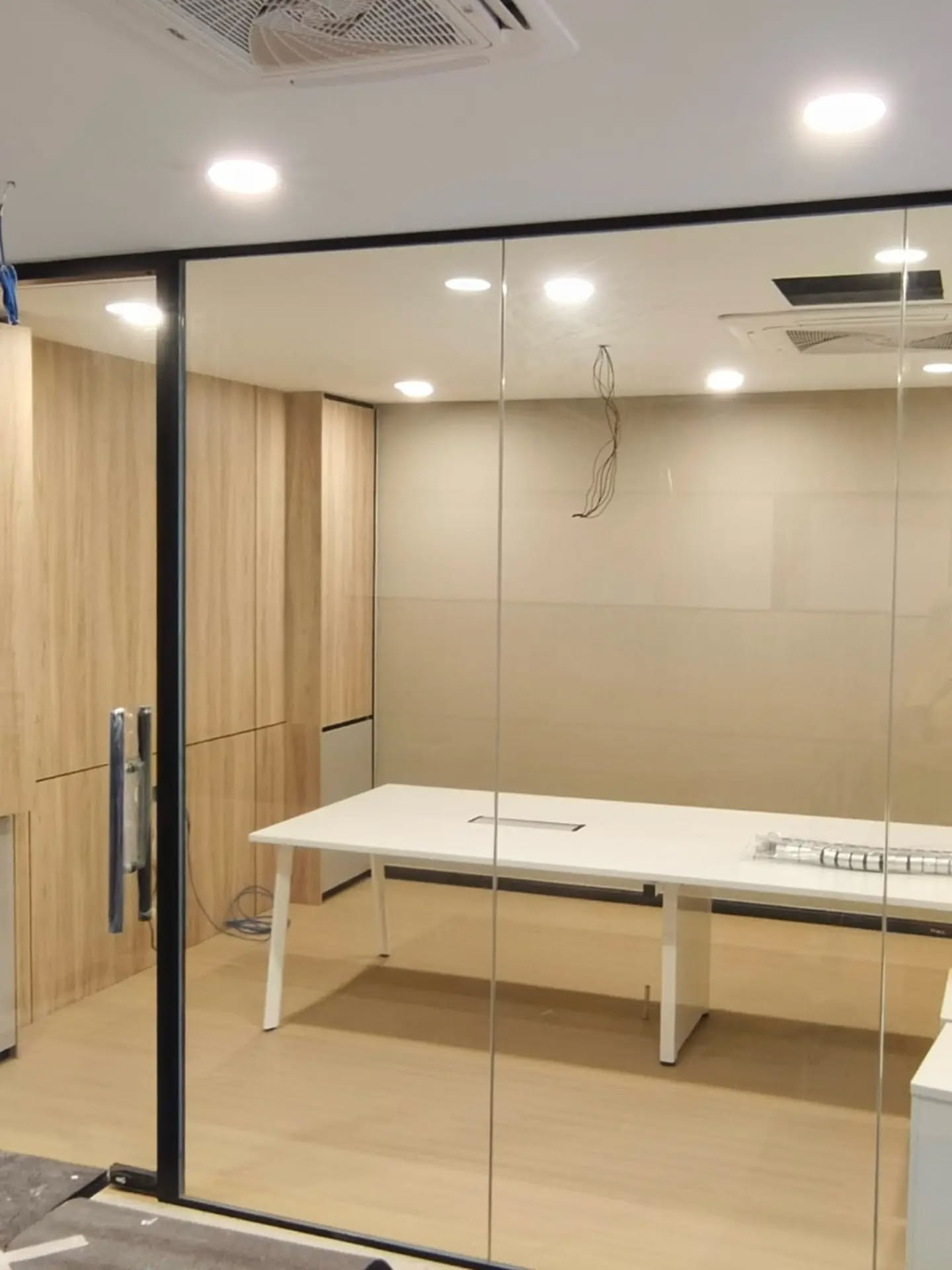 黑框钢化玻璃围成的会议室，里面放着长桌，木纹地板。